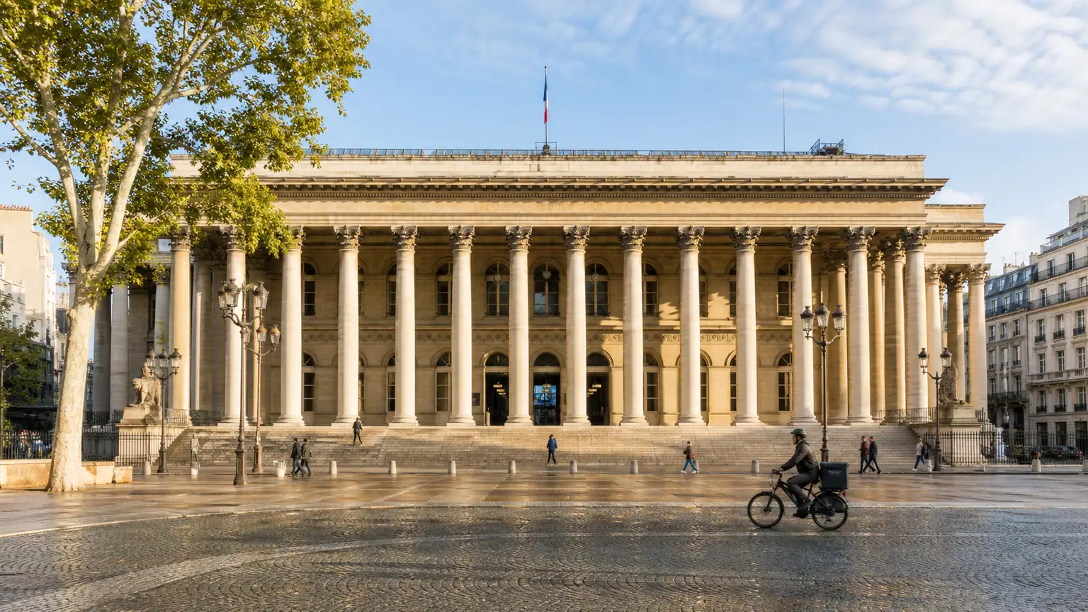 CAC 40 avant les rendez-vous américains — façade à colonnades de la Bourse de Paris au matin, passants et cycliste devant le pavé humide.