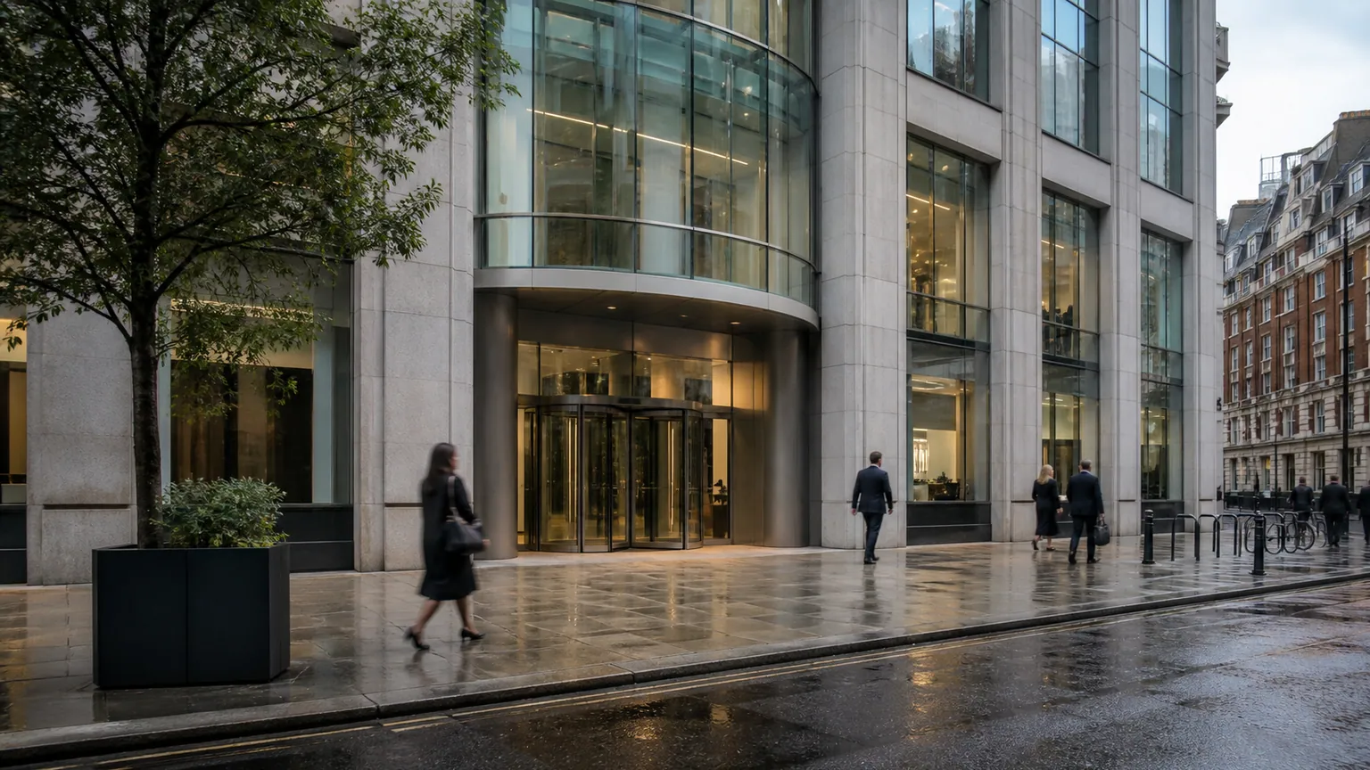 Fitch maintient la note de la France — façade vitrée d'une agence de notation, passants anonymes et chaussée humide en fin de journée.