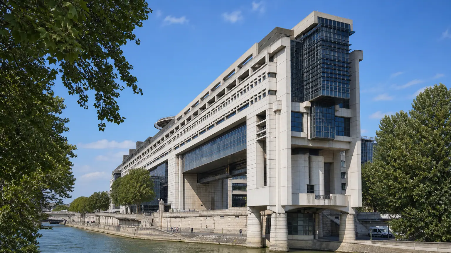 Budget de l’État et loi spéciale — vaste architecture administrative à Bercy au bord de la Seine, sous une lumière matinale claire.