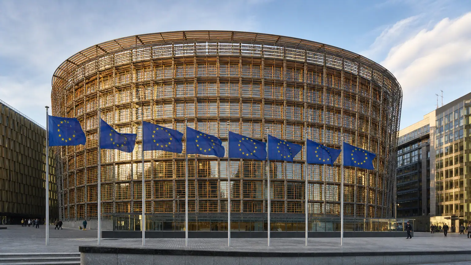 Réduction du budget européen — bâtiment Europa à Bruxelles, drapeaux de l'Union européenne au premier plan et passants lointains sur l'esplanade.