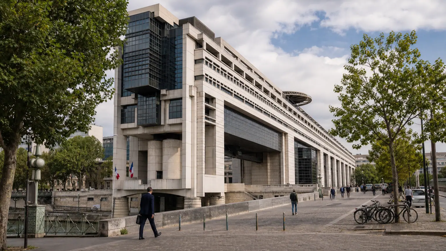 Surtaxe des grandes entreprises envisagée pour 2027 — vaste façade de Bercy à Paris, drapeaux français et passants sur le parvis.