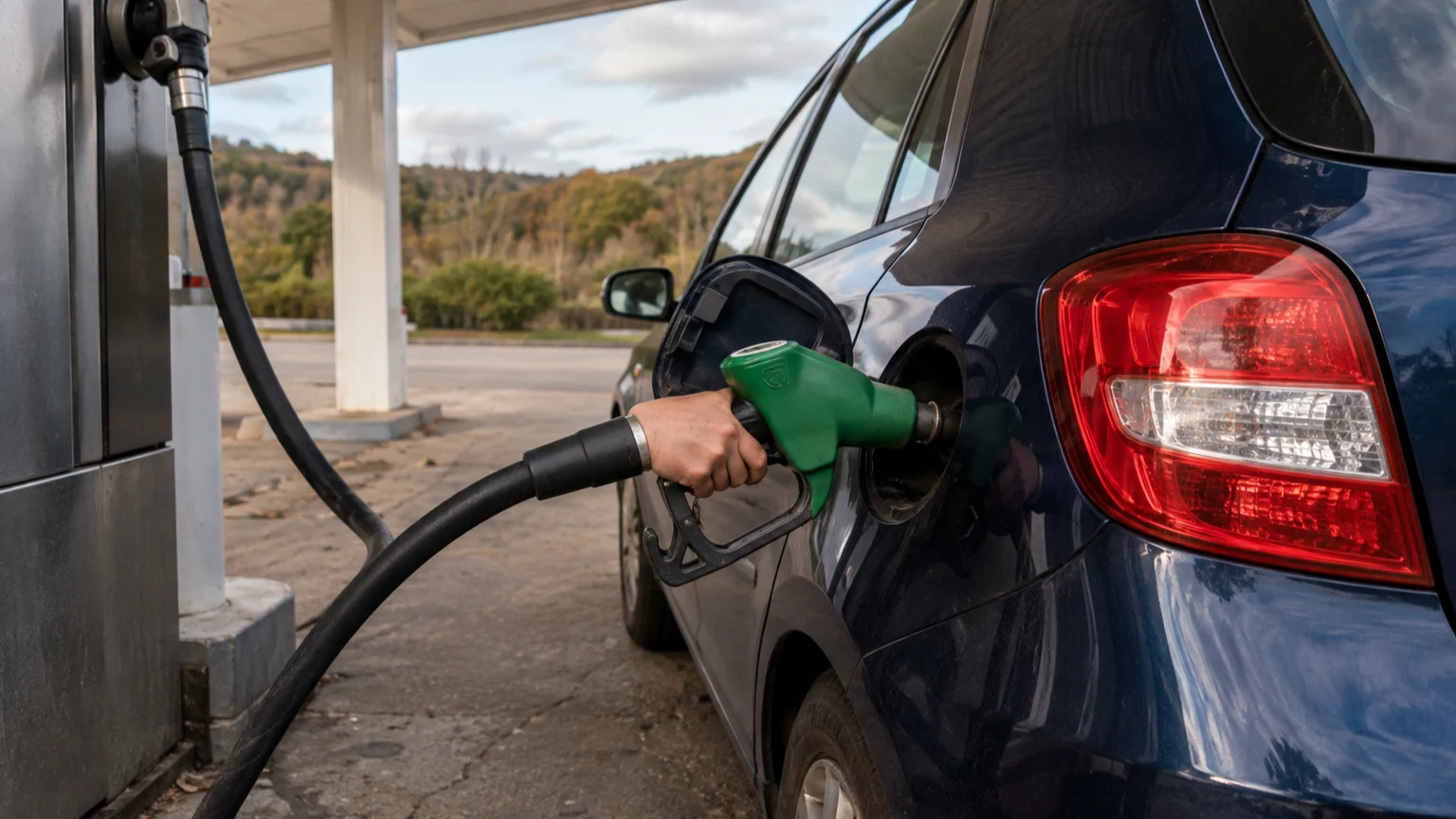 Aide carburant pour les grands rouleurs — pistolet vert inséré dans le réservoir d'une voiture thermique à une station-service française.