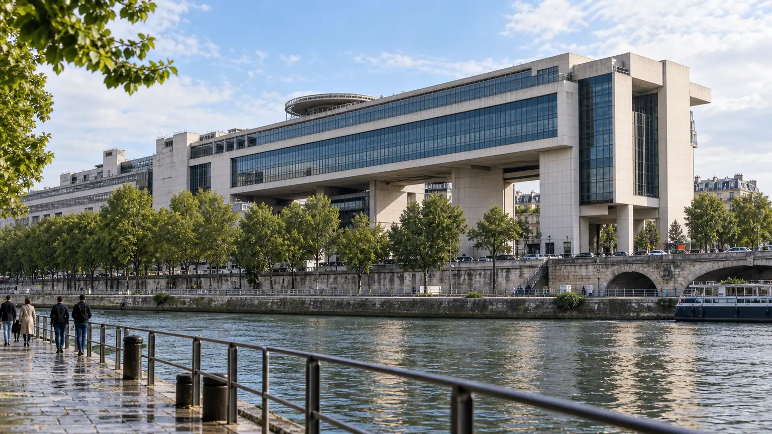 Crédits budgétaires à Bercy — façade monumentale du ministère de l’Économie et des Finances au bord de la Seine, avec quai mouillé et passants lointains.