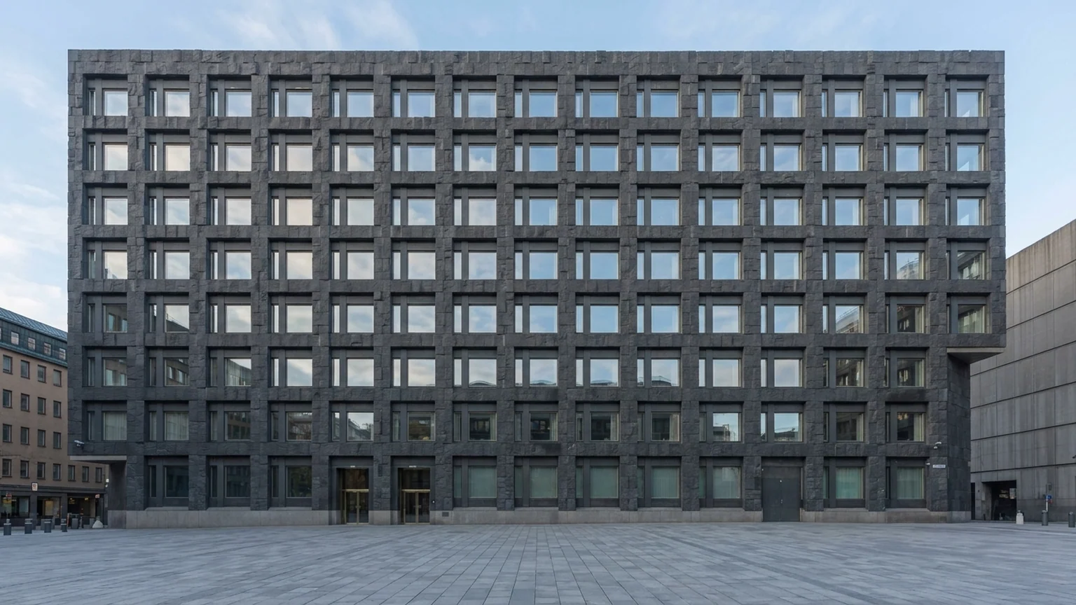 Décision de la Riksbank sur les taux suédois — façade moderniste en blocs de granit sombre et parvis minéral à Stockholm sous un ciel d'automne scandinave.
