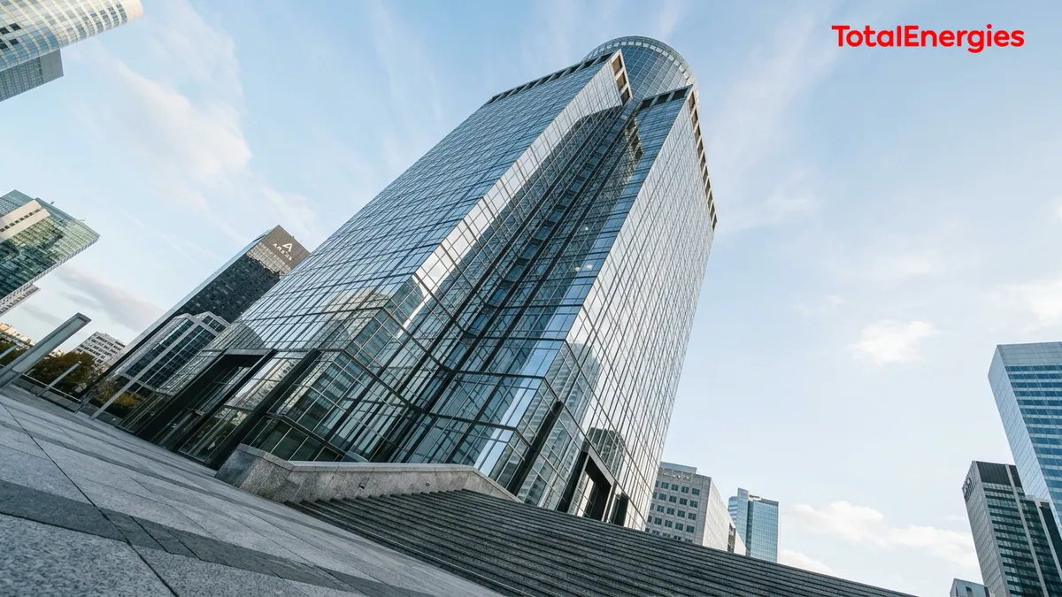 Rachats d'actions du groupe TotalEnergies — tour de bureaux vitrée à La Défense sous la lumière matinale avec le logo officiel en haut à droite.