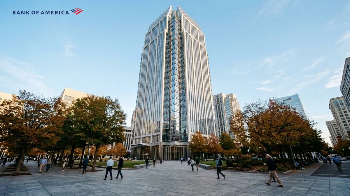 Bank of America sanctionnée par les régulateurs — tour moderne s'élevant au-dessus d'un parvis en granit bordé d'arbres d'automne, logo officiel de l'enseigne en haut à gauche.