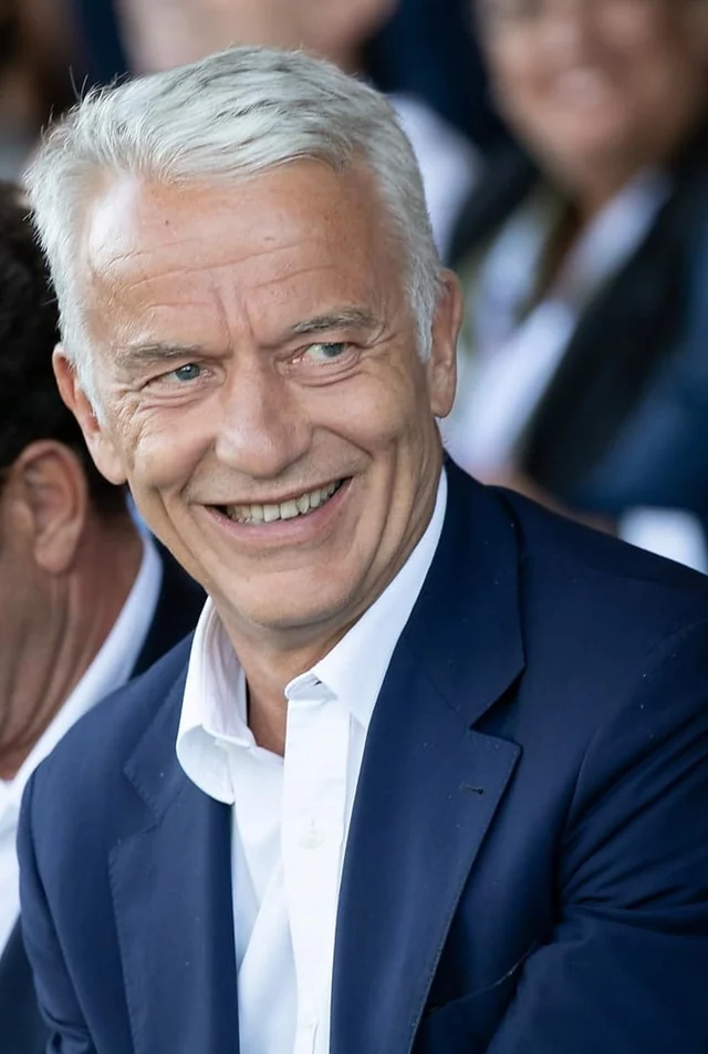 Contestation patronale des prélèvements du projet de budget — portrait de Patrick Martin souriant, en costume bleu marine et col ouvert.