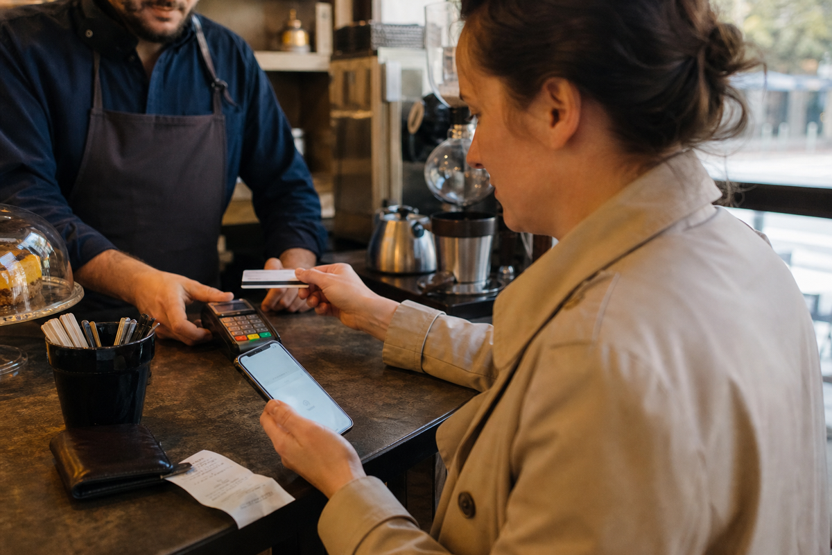 Paiement par carte au comptoir avec un terminal et un smartphone, scène réaliste en France.